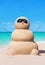Funny sandy snowman in sunglasses at tropical sunny ocean beach.