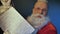 Funny Santa Claus reads magical wishes list, letter for preparing holiday gift