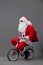 Funny Santa Claus in sunglasses and headphones with the bag with Christmas gifts on his back rides a bicycle on the