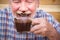 Funny scene with nice senior old man portrait drinking hot chocolate and having face dirty of it - mature people have fun ald