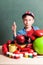 Funny schoolboy sitting at table with colorful school accessories