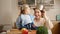 Funny shot of little baby boy with bowl on head looking at mothre with cooking pan on kitchen