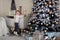 Funny sly little girl in a white sweater secretly takes New Year`s balls to decorate the Christmas tree