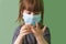Funny small girl in a protective disposable medical mask examines her hands. The cute little girl looks at her clean fingers. The
