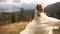 Funny smiling bride is happily shaking her head and playing with her veil in sunny golden mountains.