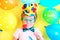 Funny smiling child clown with multicolored balloons. April fools' day celebration concept. Birthday party concept.