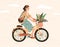 Funny smiling girl dressed in stylish clothes riding bicycle with flower bouquet in front basket. Cute happy young woman