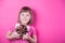 Funny smiling little girl holding pretty spotted gift box in her hands on bright pink background