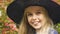 Funny smiling little girl in witch hat posing at camera, Halloween party outfit