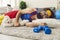 Funny smiling man in bright colorful sportswear sleeping on carpet with toy during sports workout