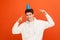 Funny smiling teenager in casual white sweatshirt with hood pointing fingers on party cap on his head, holidays organisation