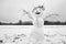 Funny snowman on snowy field with open arms made of twigs