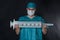 Funny surgeon in scrubs holding giant syringe