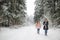 Funny teen sisters having fun on a walk in snow covered pine forest on chilly winter day. Teenage girls exploring nature