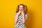 Funny teenage girl with a two-ponytail hairstyle smiles with braces grimaces and laughs on a yellow background