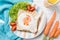 Funny toast with fried egg in a shape of chicken and fresh carrots, healthy food for kids Easter idea, top view