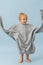 Funny toddler boy swinging sleeves of huge oversized grey thick warm shirt