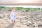 Funny toddler girl running at the beach at sunset