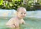 Funny toddler happily swimming in the pool on the garden
