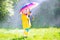 Funny toddler with umbrella playing in the rain