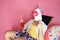 funny tourist man in unicorn mask hold beer bottle lie on deckchair on pink background studio portrait
