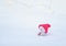 Funny toy snowman in a bright pink cap sitting in a white snowdrift with a gift on the background of glowing garlands