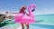 Funny Vacation Woman in bikini and inflatable pink flamingo toy float by pool