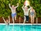 Funny view of couples of senior people playing in the blue and transparent water of the swimming pool. Man jumps into the pool