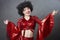 Funny vintage woman in afro wig and disco costume on a gray background