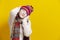 Funny Winsome Exclaiming Caucasian Blond Girl In Warm Knitted Hat and Scarf Posing with Lifted Hands While Making Faces And