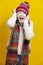 Funny Winsome Exclaiming Caucasian Blond Girl In Warm Knitted Hat and Scarf Posing with Lifted Hands While Shouting And Pulling