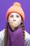 Funny Winsome Girl In Coral Knitted Seasonal Hat Posing With Chewing Gum Bubble In Front of Face Against Purple Seamless