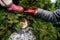 Funny winter composition a boy in a hat, a female hand and a children`s red boot