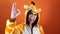 A funny woman in a big kigurumi of giraffe is smiling and showing sign of OK on an orange background. crazy and funny