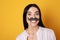 Funny woman with fake mustache on yellow background