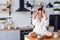 A funny woman with hair curling dressed in white bathrobe feels panic in the kitchen while cooking.