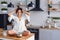 A funny woman with hair curling dressed in white bathrobe feels panic in the kitchen while cooking.