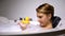 Funny woman looking at rubber duck during bathing with bubbles, childish mood