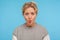Funny woman with short curly hair in casual grey sweatshirt making fish face with pout lips and big eyes