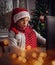 Funny wondering boy sitting in front of laptop wearing red Santa cap having Christmas meeting.