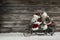 Funny wooden christmas background with two santa claus on a bicycle making xmas shopping.