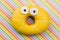 Funny yellow donut on colorful background.