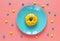 Funny yellow donut with eyes on a blue plate.