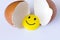 Funny yellow smiley toy in an egg-shell. On white background