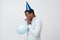 Funny young african guy inflating the balloon wearing blue party hat.