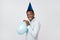Funny young african guy inflating the balloon wearing blue party hat.