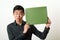Funny young Asian man showing green copy space box and looking s