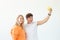 Funny young couple in love cute man and charming woman making selfie on vintage yellow film camera posing on a white