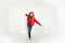 Funny young curly brunette girl in casual red hoodie jeans runs on white background. Teenagers lifestyle concept. Copy space. Is