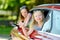 Funny young girls sticking their heads out the car window looking forward for a roadtrip or travel